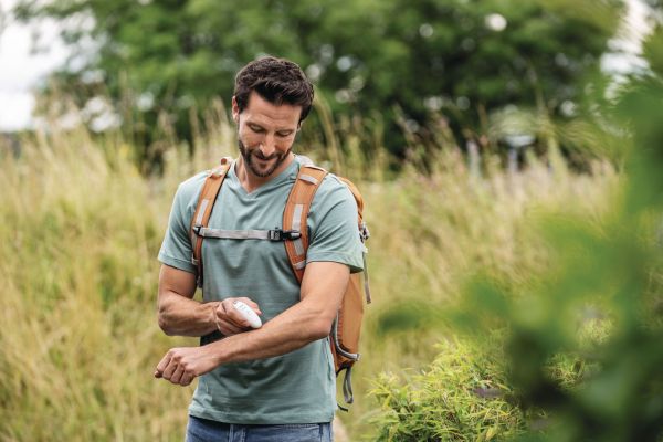 A sporty man with a rucksack out in nature uses the BR 10 Insect Bite Healer.