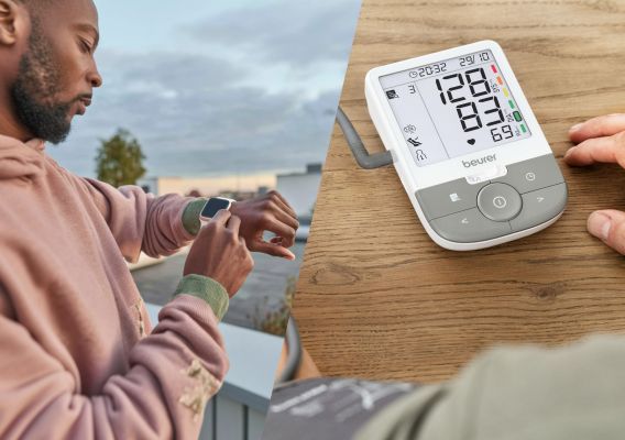 A young man wearing a hoodie stands outdoors and looks at his smartwatch. Next to him is a picture of a Beurer blood pressure monitor on a table.