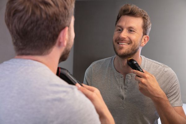 A man stands in front of the mirror and shaves his beard with the Beurer MN9X.