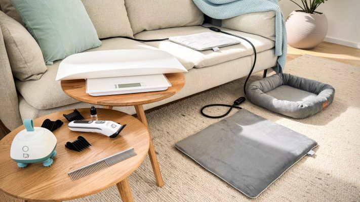 Die „Love Your Pet by beurer"-Produkte sind in einem Wohnzimmer mit Sofa, Tischchen und Teppich zu sehen.