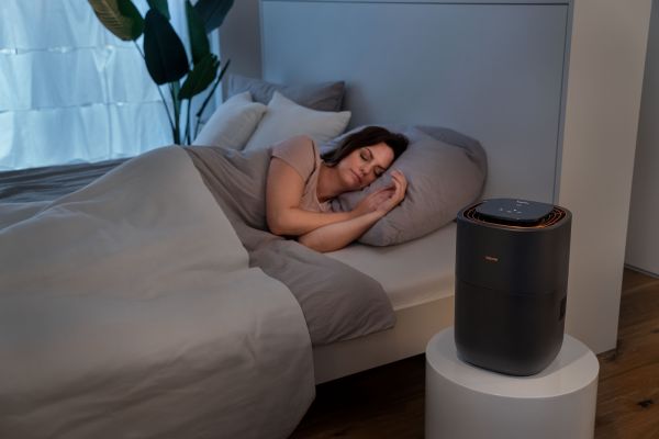 A woman is sleeping in bed, next to her the Beurer LB 300 and the ETM seal