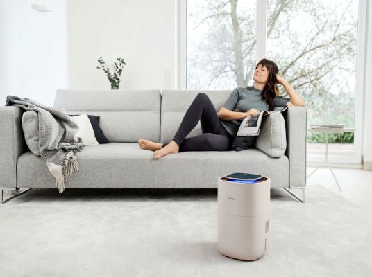 Eine dunkelhaarige Frau liegt auf einem Sofa, neben ihr der LB 300 Plus Sand.