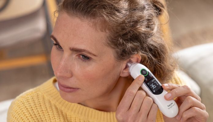 Eine Frau misst die Temperatur im Ohr mit dem Beurer EarSense Ohrthermometer