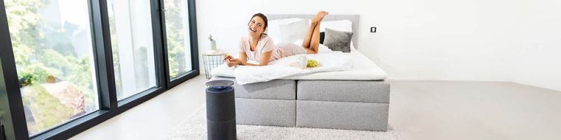 Joven mujer relajada en la cama y el purificador de aire Beurer LR 401 en primer plano