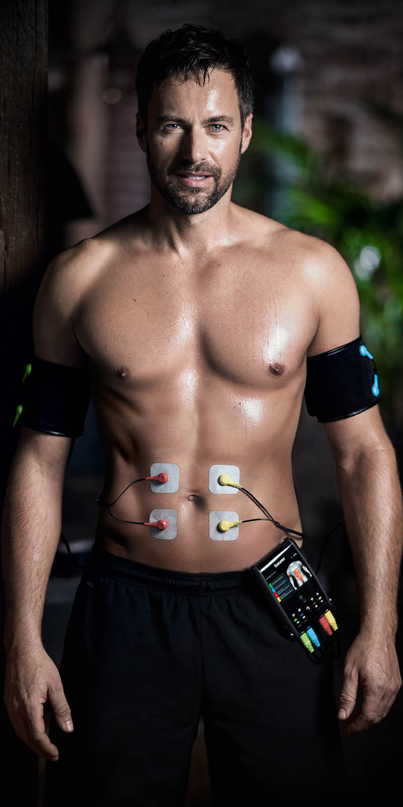 Dispositivo EMS Beurer EM 95 - immagine applicativa L'uomo ha elettrodi sullo stomaco e manette sul braccio