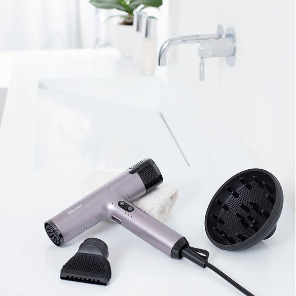 Secador de pelo Beurer HC 100 está en el baño sobre el borde del lavabo, al lado los dos accesorios