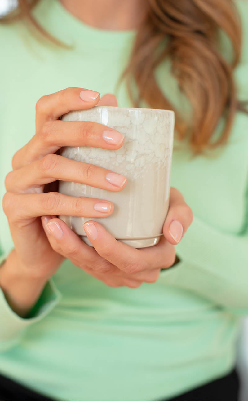 Ritagli di una donna che tiene una bella tazza e si vedono le sue unghie ben curate