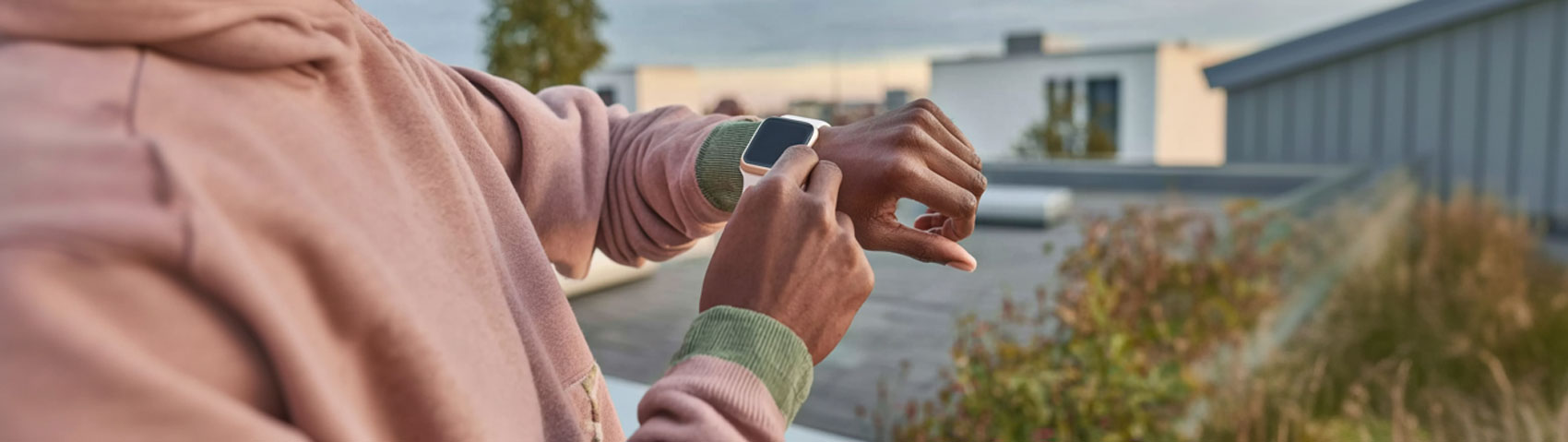Un homme se tient sur un balcon et regarde son AppleWatch